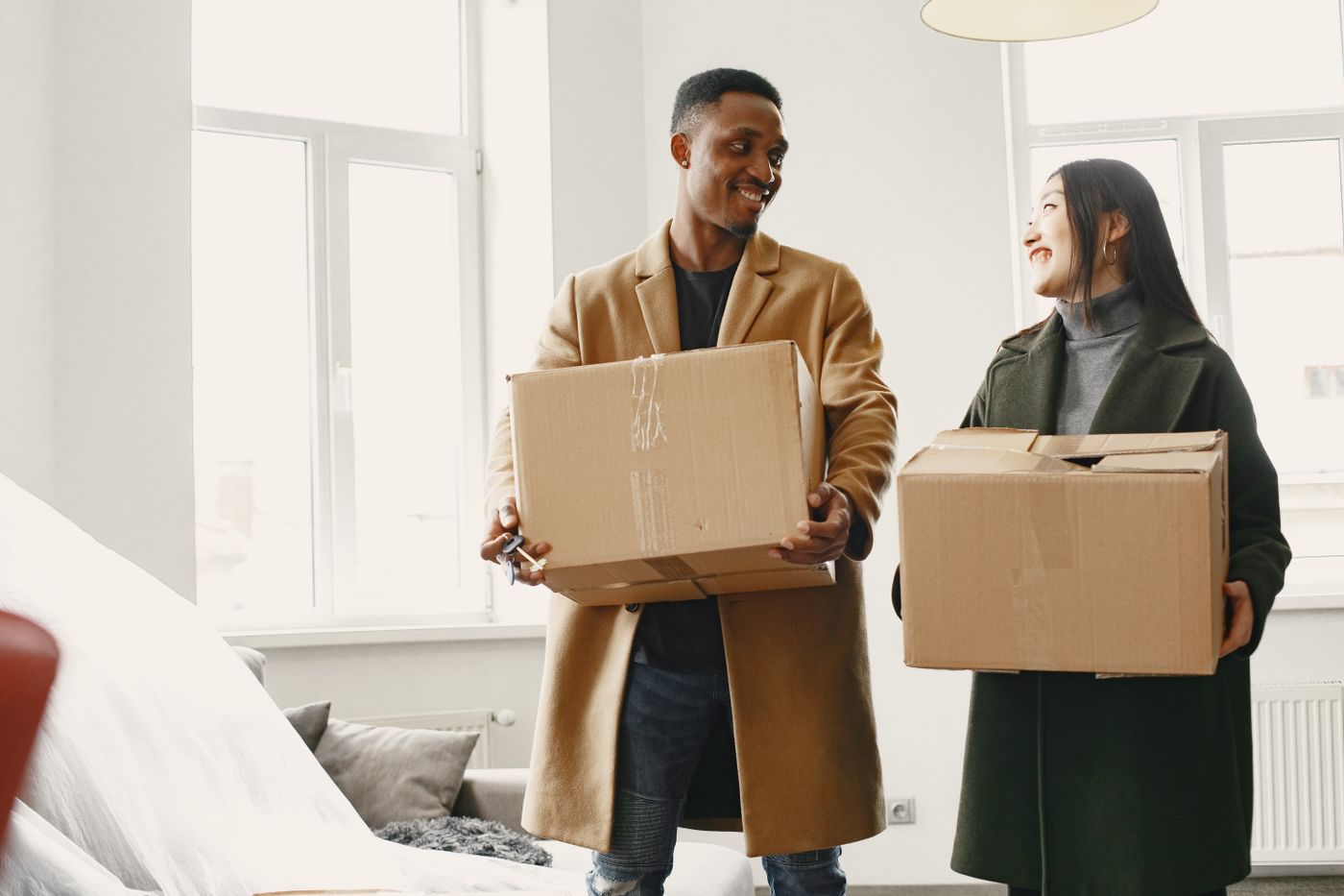 A couple carrying moving boxes into their new home